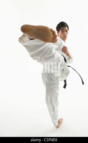 Maschio asiatici karate cintura nera di calci in aria Foto Stock