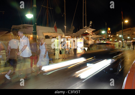 Auto percorrendo il lungomare del porto la sera a St Tropez, sud della Francia. Foto Stock