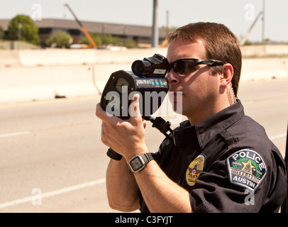 Maschio di funzionario di polizia utilizza il radar di velocità la pistola per la cattura di velocizzare i driver su autostrada in Austin Texas USA Foto Stock