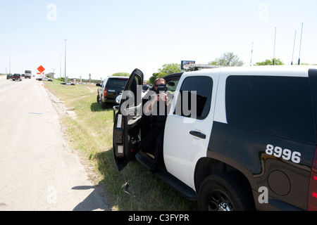 Maschio di funzionario di polizia utilizza il radar di velocità la pistola per la cattura di velocizzare i driver su autostrada in Austin Texas USA Foto Stock