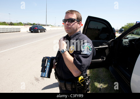 Maschio di funzionario di polizia utilizza il radar di velocità la pistola per la cattura di velocizzare i driver su autostrada in Austin Texas USA Foto Stock