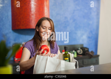 Incinta donna caucasica disimballaggio generi alimentari in cucina Foto Stock