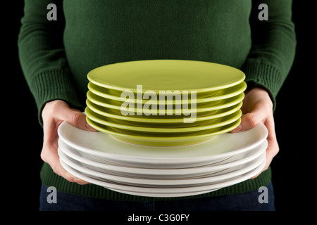 Mani femminili tenendo un mucchio di verde e piatti bianchi Foto Stock