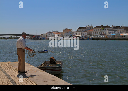 Pescatore si lega a un dinghy in Tavira, Algarve, PORTOGALLO Foto Stock