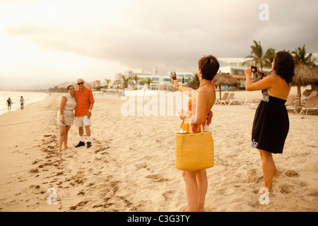 Famiglia in vacanza in spiaggia prendendo fotografie Foto Stock