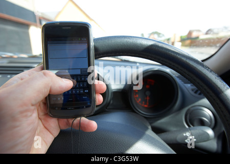 Uomo che utilizza il touchscreen Android telefono cellulare per inviare un messaggio di testo durante la guida Foto Stock