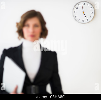 Imprenditrice sfocati con office orologio che mostra il tempo in background Foto Stock