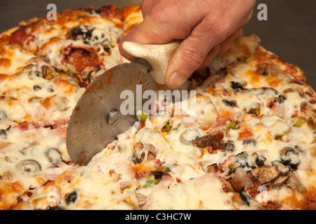 Persona per affettare la pizza fatta in casa torta USA Foto Stock