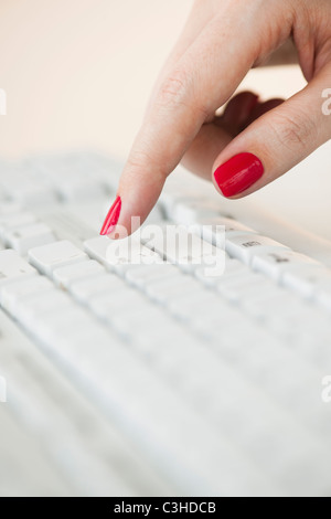 Close up della donna di dito con red Nail Polish digitando sulla tastiera del computer Foto Stock