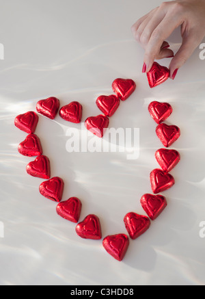 Close up della donna di mano con red Nail Polish messa a forma di cuore da cioccolatini Foto Stock