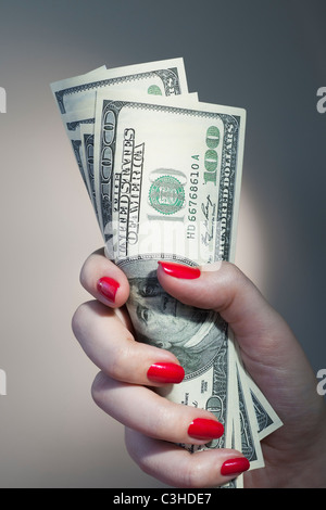 Close up della donna di mano con red Nail Polish holding mazzetto di banconote di dollari Foto Stock
