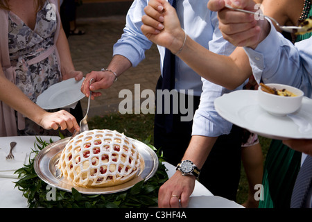 Gli ospiti godono torta al ricevimento di nozze Foto Stock