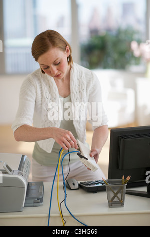 Donna installazione router presso l'ufficio domestico Foto Stock