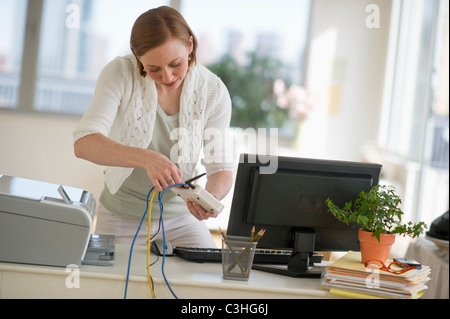 Donna installazione router presso l'ufficio domestico Foto Stock