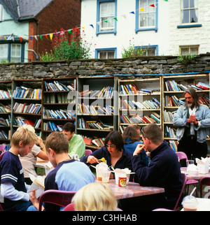 La gente teenager ragazzi mangiare noodle accanto a libri su librerie in un caffè all'aperto presso la libreria di onestà nel Castle Grounds durante il Hay Book Festival Hay on Wye, Galles UK KATHY DEWITT Foto Stock