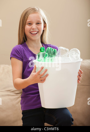 Ritratto di ragazza (8-9) tenendo il contenitore di riciclaggio con bottiglie di plastica Foto Stock