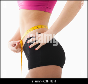 Giovane donna cintura di misurazione Foto Stock