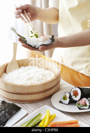 Primo piano delle mani rendendo sushi arrotolato a mano Foto Stock