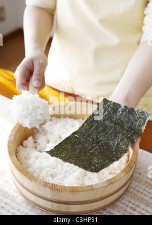 Primo piano delle mani rendendo sushi arrotolato a mano Foto Stock