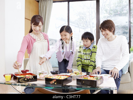 I genitori e i bambini a mangiare la visualizzazione di fiori in box pranzo Foto Stock