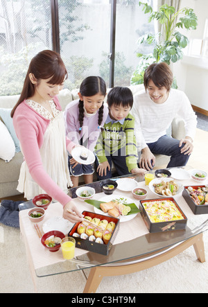 I genitori e i bambini a mangiare la visualizzazione di fiori in box pranzo Foto Stock