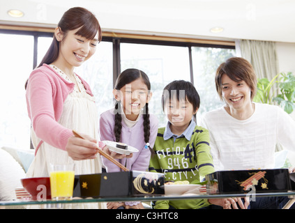 I genitori e i bambini a mangiare la visualizzazione di fiori in box pranzo Foto Stock