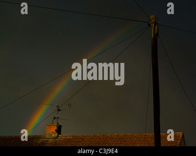 Antenna televisione,i cavi telefonici,comignolo e Rainbow su un tetto. Foto Stock