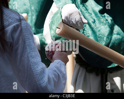 Un bambino la raccolta di cera di candela da un Nazareno durante la Semana Santa (Pasqua) processioni in Spagna a Malaga, Aprile 2011 Foto Stock