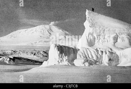 Un membro di Robert Scott Terra Nova Expedition sulla punta di un iceberg in Antartide nel 1911 con il Monte Erebus in background. Foto Stock