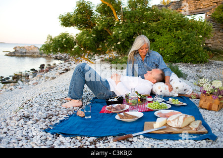 Coppia matura avente picnic sulla spiaggia Foto Stock