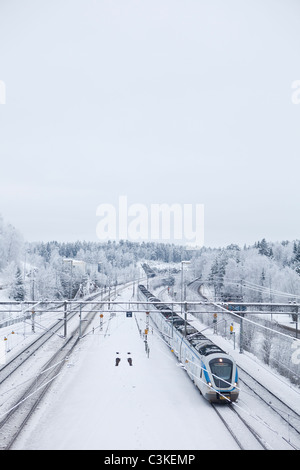 Treni passeggeri su rotaia in inverno, vista in elevazione Foto Stock