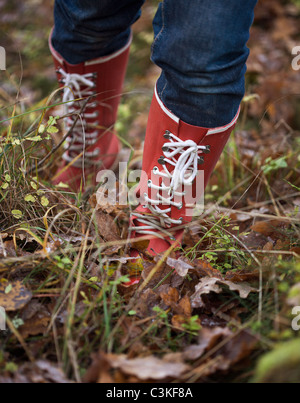 Gambe di metà donna adulta indossare stivali di gomma in piedi in erba Foto Stock