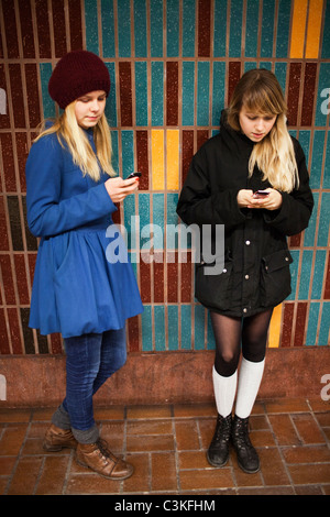 Due ragazze adolescenti utilizzando i telefoni cellulari Foto Stock