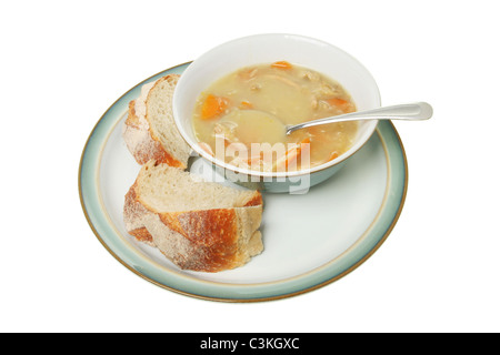 Il pollo e la zuppa di verdure in una ciotola con un cucchiaio e chunky il pane su una piastra Foto Stock