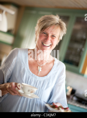 Ritratto di donna che porta tazze tè e sorridente Foto Stock