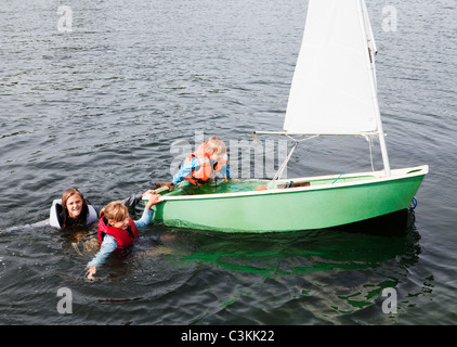 Tre bambini che cercano di entrare in gommone Foto Stock