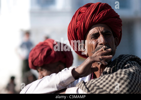 Uomo indiano fumatori tradizionali che indossa abiti di Rajasthani. Foto Stock