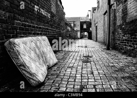 Oggetto di dumping spazzatura materasso in un vicolo urbano monocromatico Foto Stock