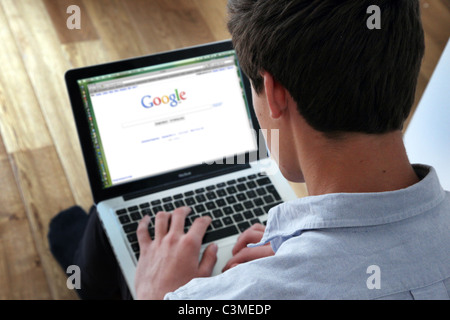 Giovane uomo utilizzando laptop sulla home page di Google. Foto Stock