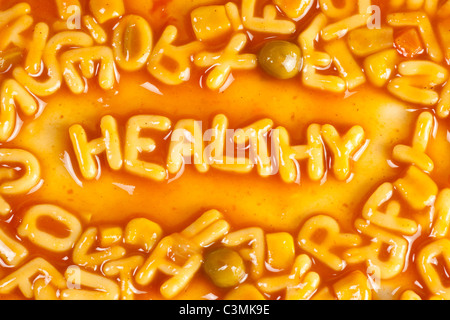 Alfabeto pasta sagomato formante la parola sano nella salsa di pomodoro Foto Stock