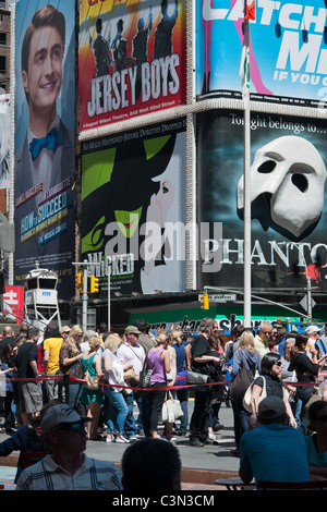 Pubblicità per gli spettacoli di Broadway e la linea per TKTS metà-prezzo biglietti è visto in Times Square a New York Foto Stock