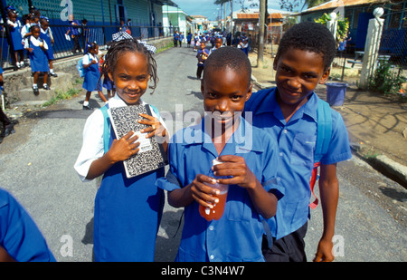 Villaggio Dennery St Lucia bambini al di fuori di San Pietro ragazzo scuola tenendo la bottiglia di succo di frutta e la ragazza con la scuola prenota Foto Stock