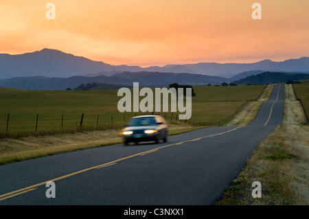 Golden sunrise luce sul lungo rettilineo di due corsie stradali del paese e le colline di primavera, Santa Ynez Valley, California Foto Stock