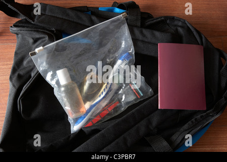 Il bagaglio a mano pranzo per un rapido viaggio tra cui un passaporto in corso di validità e di articoli da toeletta nel vedere attraverso il sacchetto in plastica Foto Stock