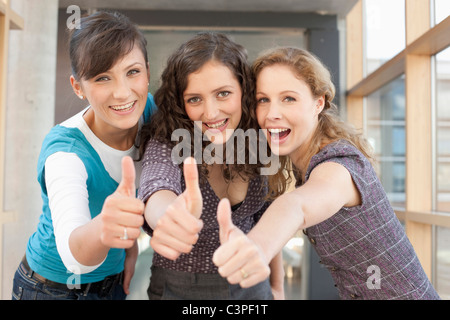 Germania, Lipsia, gli studenti universitari che mostra Thumbs up, sorridente, ritratto Foto Stock