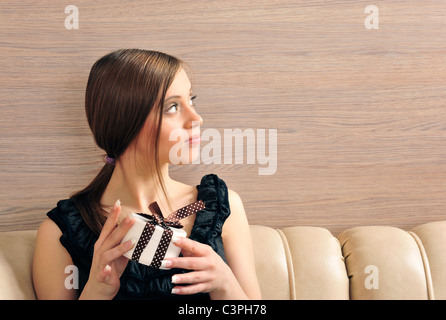 Ritratto di una giovane e bella donna che offre un presente. Sfondo di Office. Lei sta cercando a destra su copyspace Foto Stock