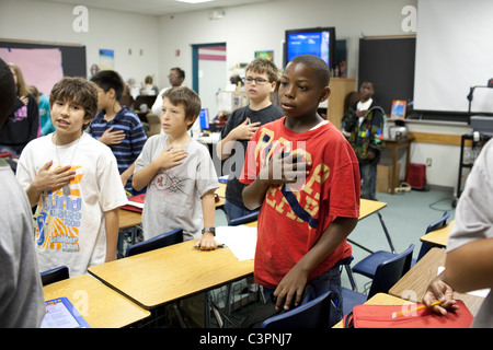 Scuola media alta junior studenti stand all'inizio della classe con la mano sul cuore a recitare il giuramento di fedeltà Foto Stock