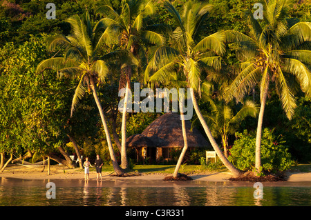 Coppia sulla spiaggia di fronte all' bure camera ospiti a Matangi Private Island Resort Fiji. Foto Stock