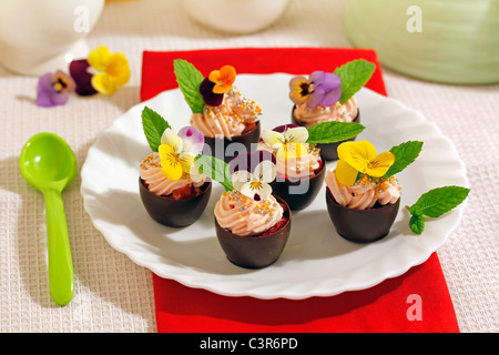 Coppe di cioccolato con panna e fiori. Ricetta disponibile. Foto Stock