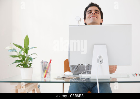 Uomo che lavora al computer sorridente Foto Stock